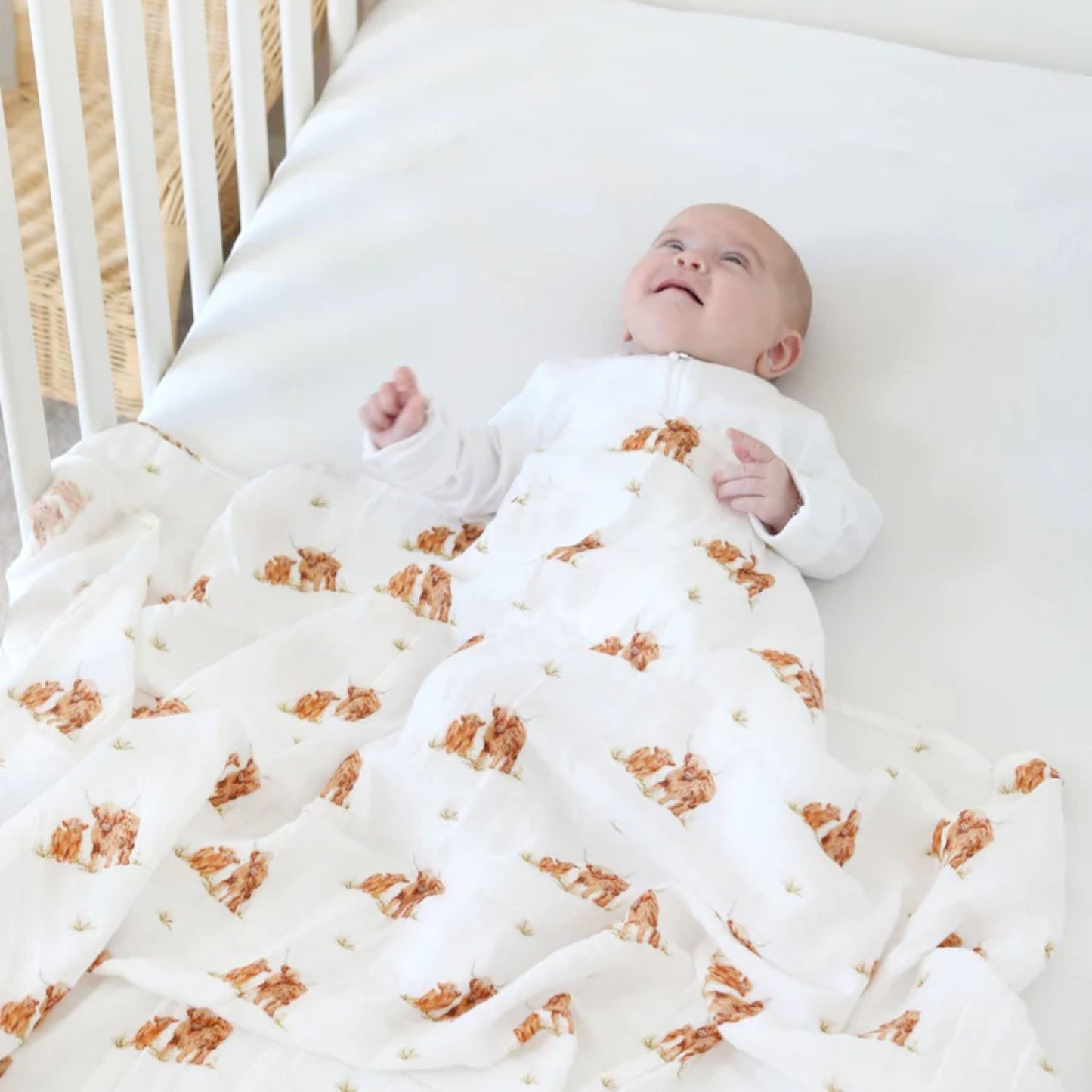 Baby lying on a white blanket with bear pattern in a crib