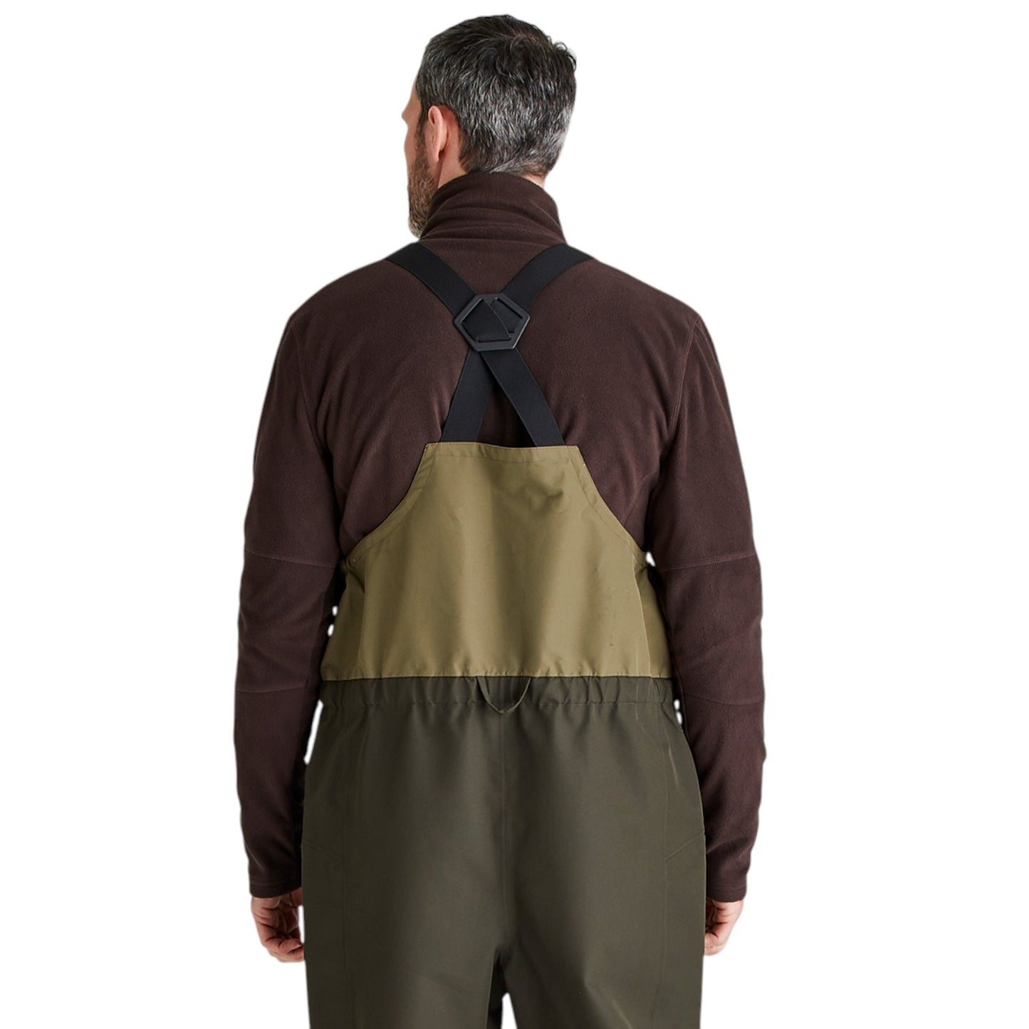 A man viewed from the back wearing a three-color waders suit over a dark brown fleece shirt. The waders feature a dark brown upper section, an olive green bib panel, and dark olive green legs, with black suspenders.