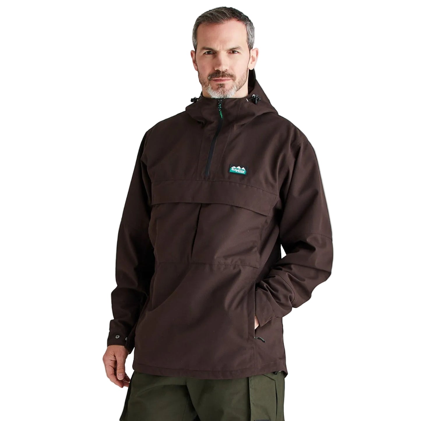 A man wearing a dark brown hooded pullover jacket with a small green and blue logo on the left chest, paired with olive green pants, photographed against a light gray studio background.