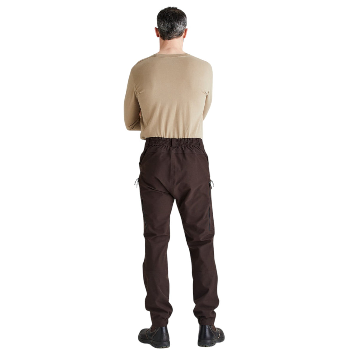 A man viewed from behind wearing a beige long-sleeve shirt and dark brown cargo pants against a plain white background.