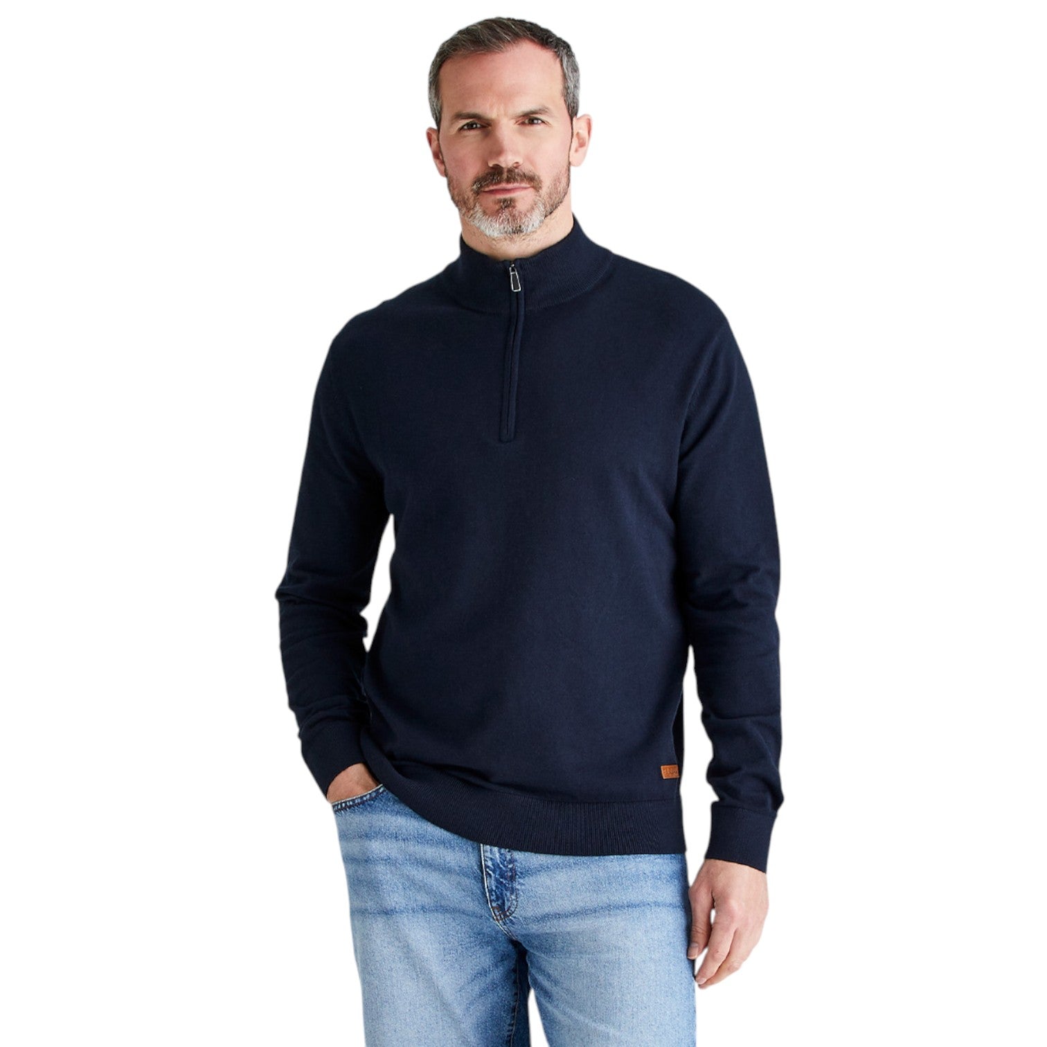 A man wearing a dark navy blue quarter-zip knit sweater and light blue jeans, standing against a plain white background.