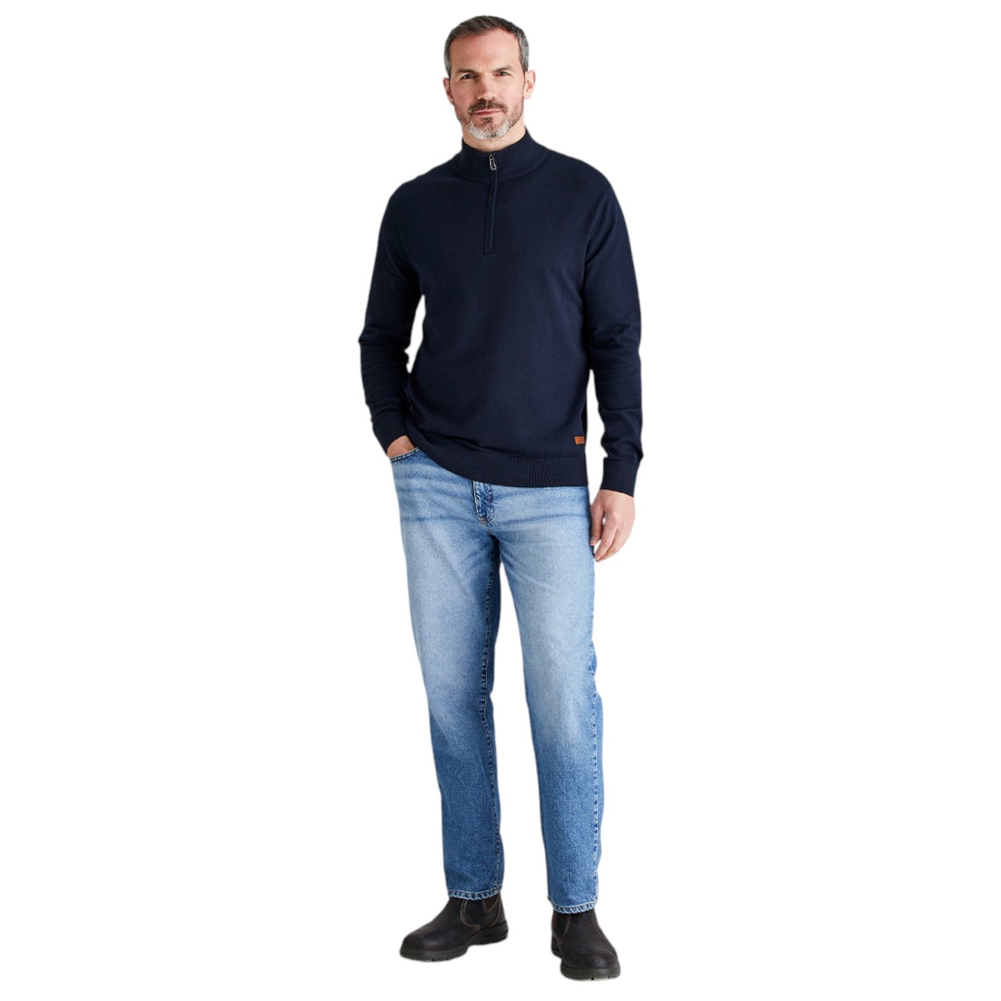 A man wearing a navy blue quarter-zip pullover sweater and light blue jeans, standing against a plain white background.