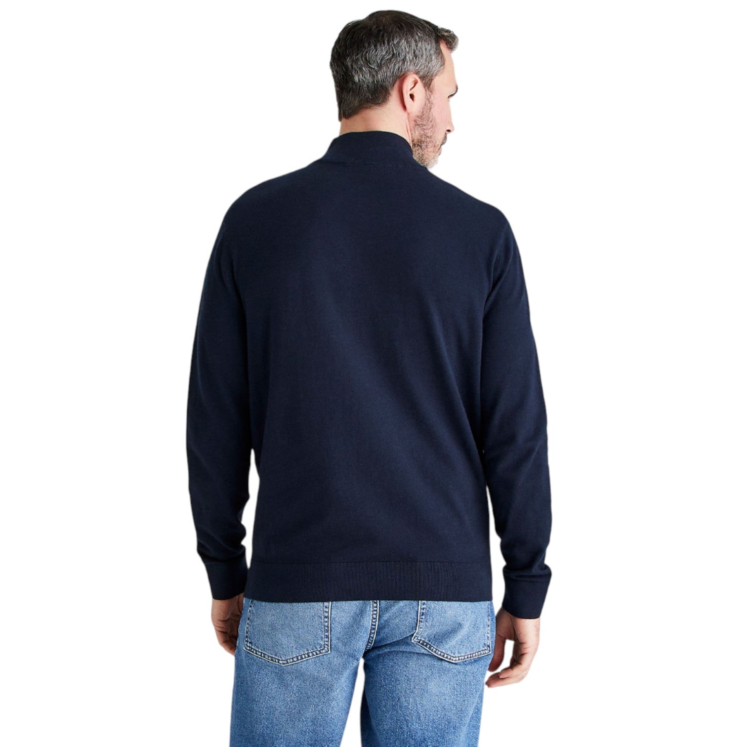 A man viewed from the back wearing a dark navy blue knit sweater and blue jeans against a plain white background.