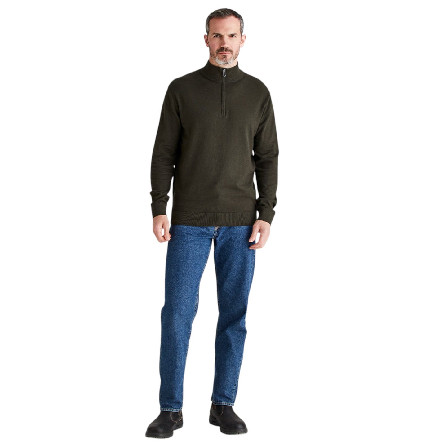 A man wearing an olive green quarter-zip pullover sweater and blue jeans, standing against a plain white background.