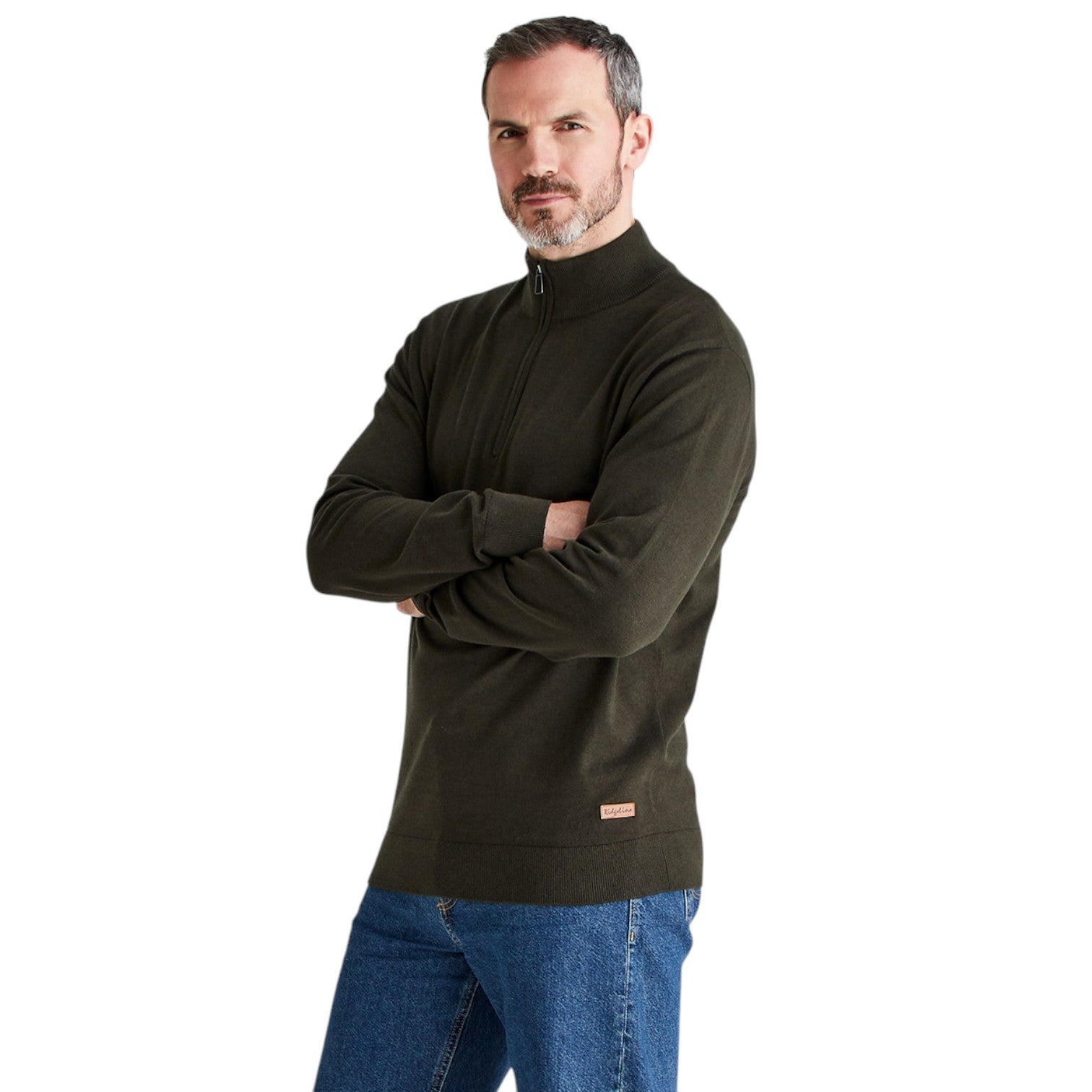 A man wearing a dark olive green quarter-zip pullover sweater and blue jeans, standing with his arms crossed against a plain white background.