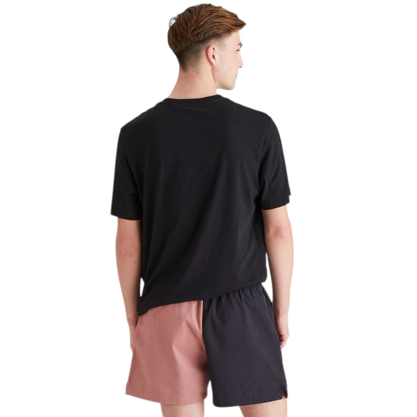 Person wearing a black t-shirt and pink shorts on a white background