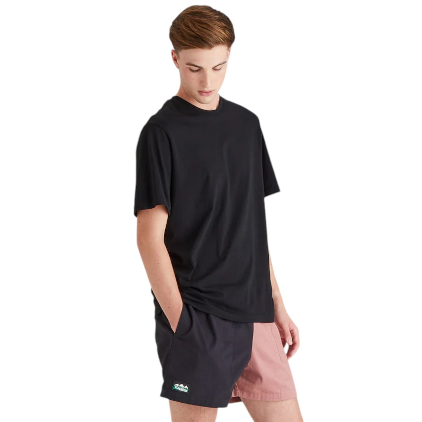 Person wearing a black oversized t-shirt and pink shorts on a white background