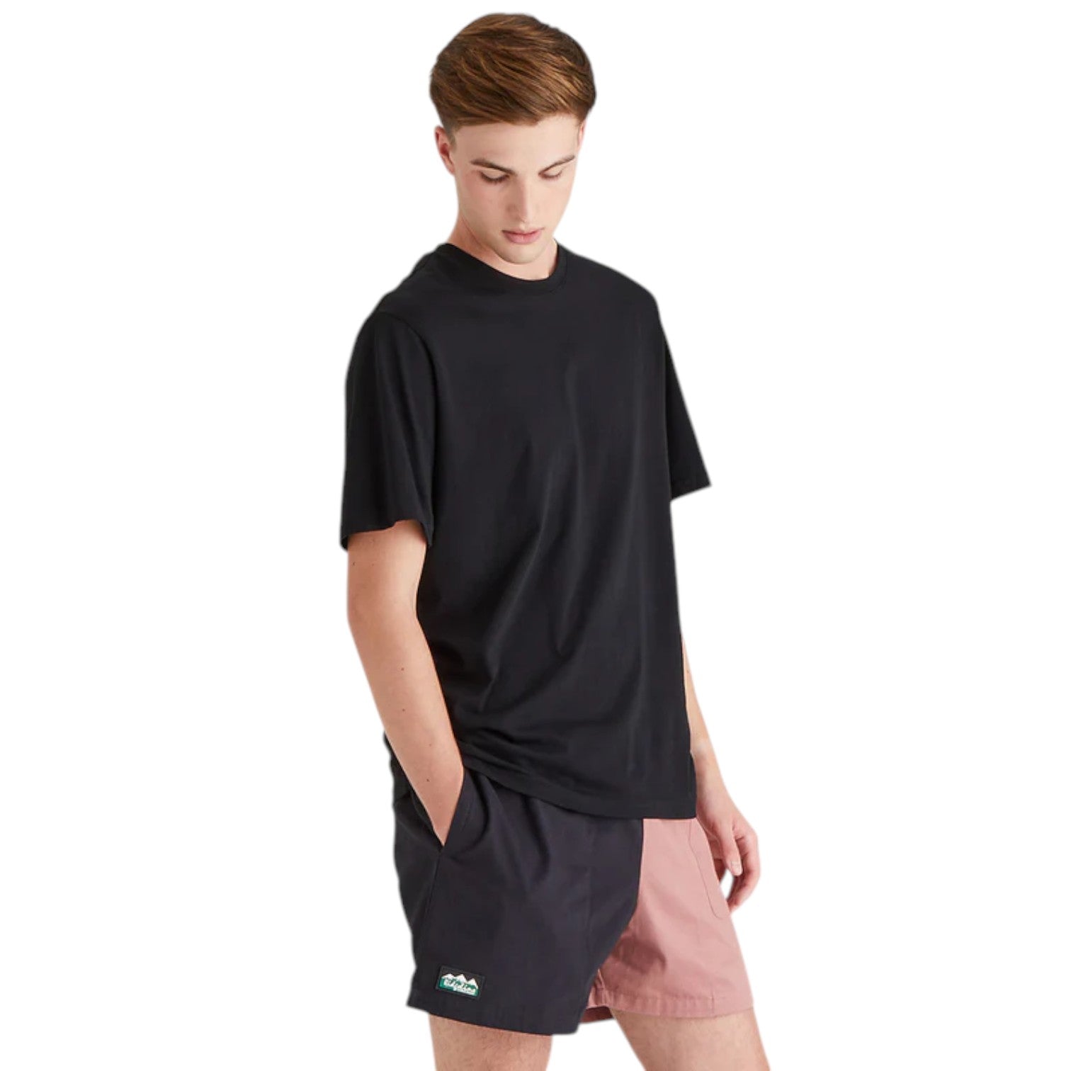 Person wearing a black oversized t-shirt and pink shorts on a white background