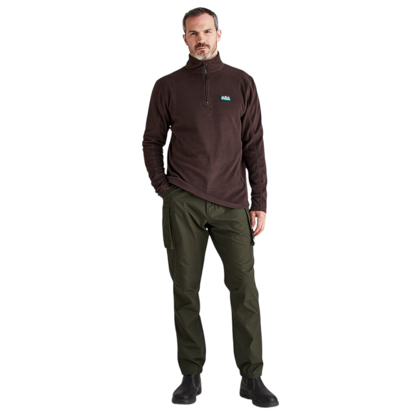 A man modeling a dark brown quarter-zip fleece pullover with a small blue and white logo on the left chest, paired with olive green pants and black shoes, against a plain white background.