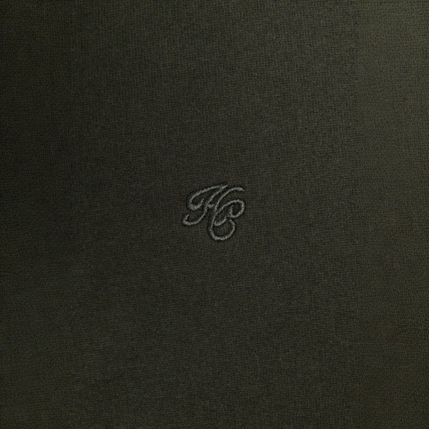 Dark fabric surface with a small embroidered logo in the center
