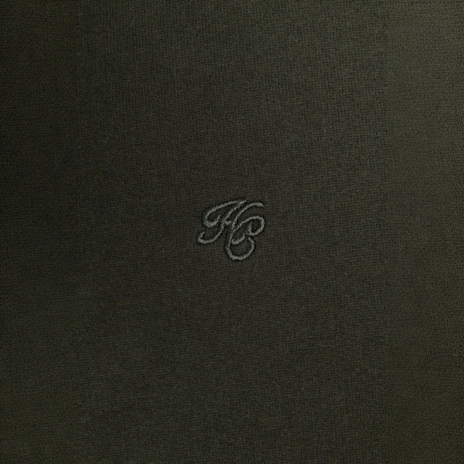 Dark fabric surface with a small embroidered logo in the center