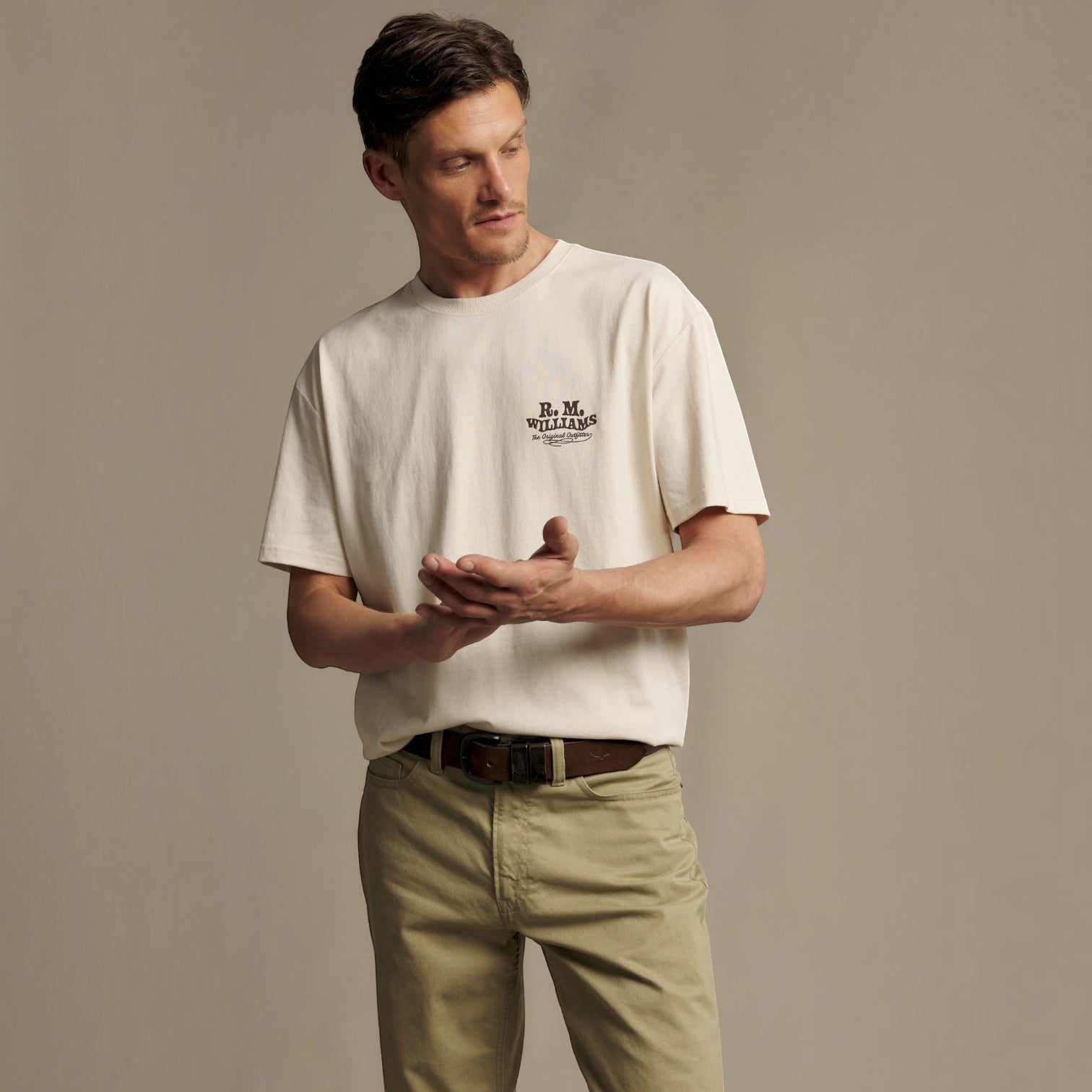 A man wearing a cream-colored short-sleeve t-shirt with a black 'B.M.