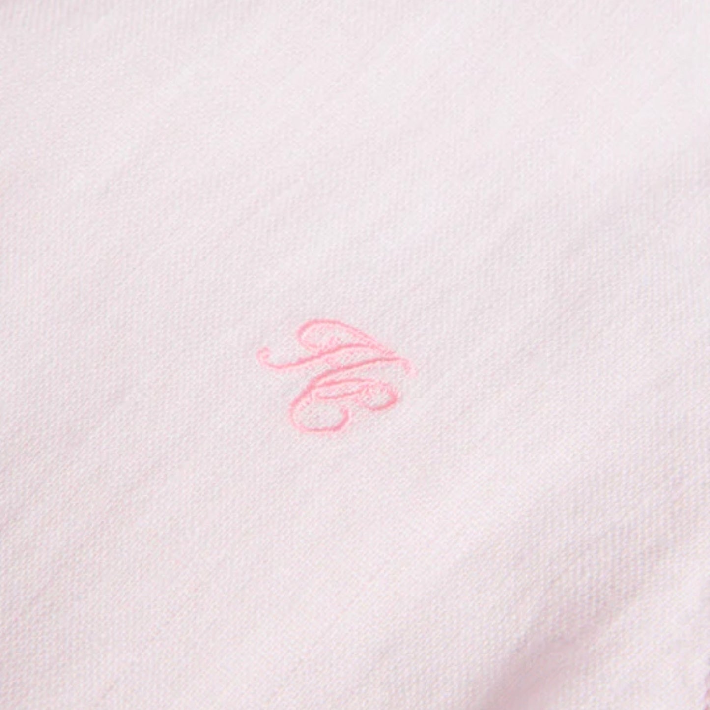 Close-up of a pink embroidered design on a white fabric background