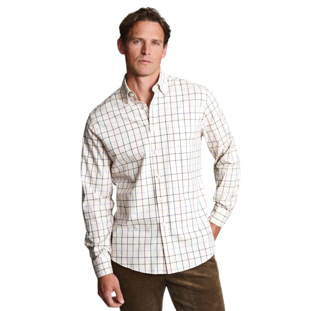 A man wearing a long-sleeve button-down shirt with a white base and a subtle red and blue windowpane plaid pattern, paired with brown trousers, against a solid white background.
