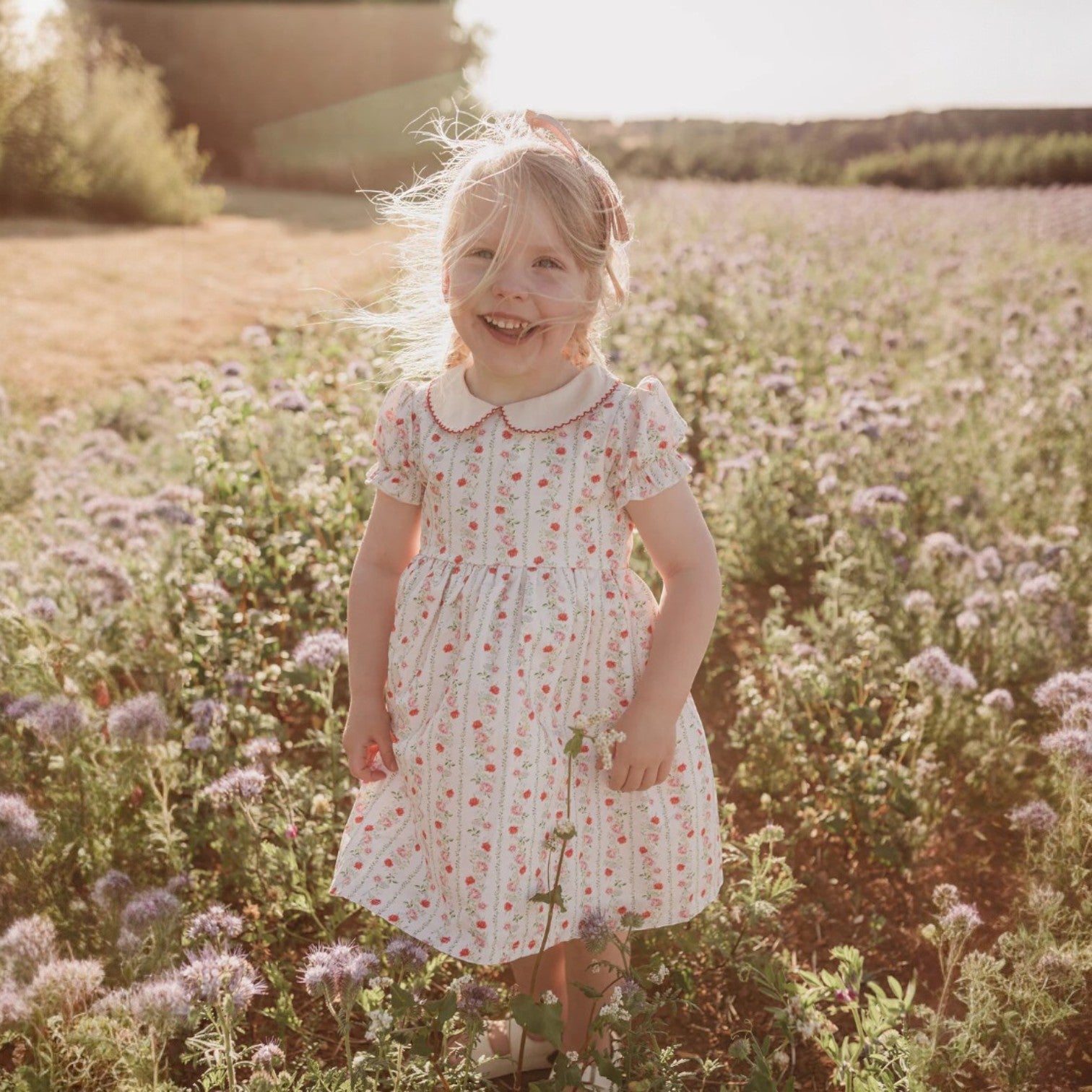 Young girl in a floral dress standing in a field of flowers.