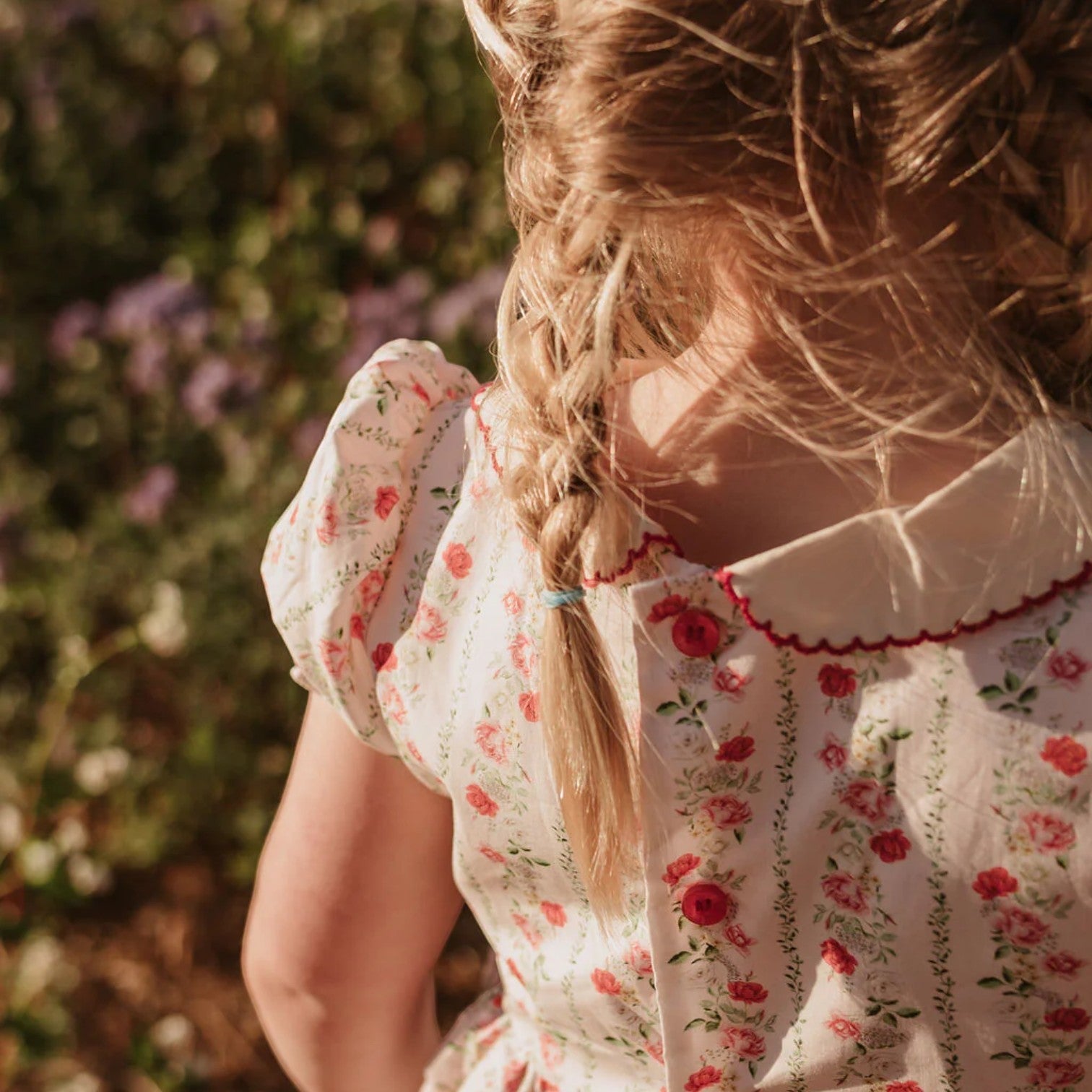 Person wearing a floral dress with braided hair in a garden setting