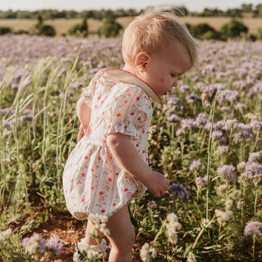 Child in a floral dress standing in a field of lavender.