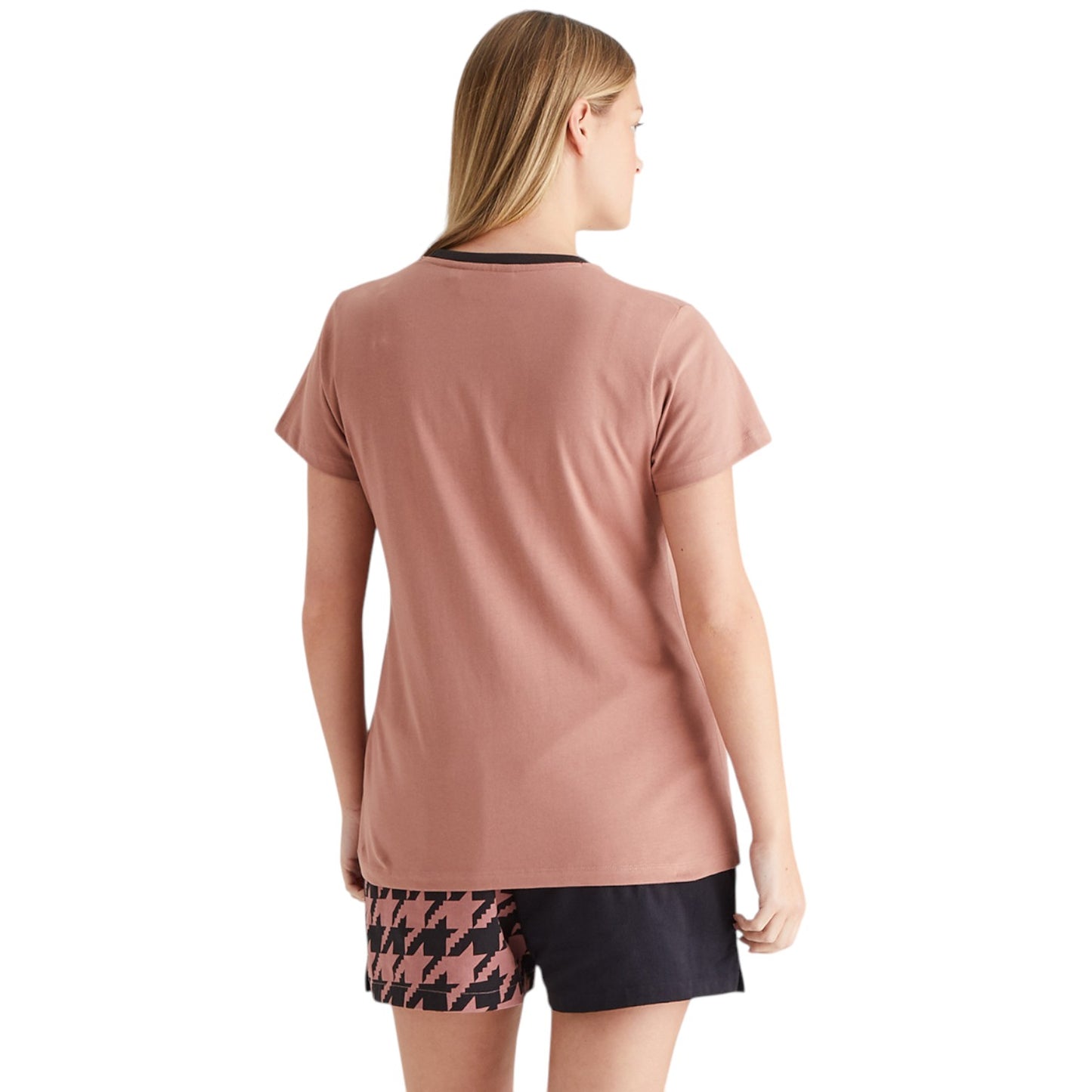Woman wearing a pink t-shirt and patterned shorts on a white background