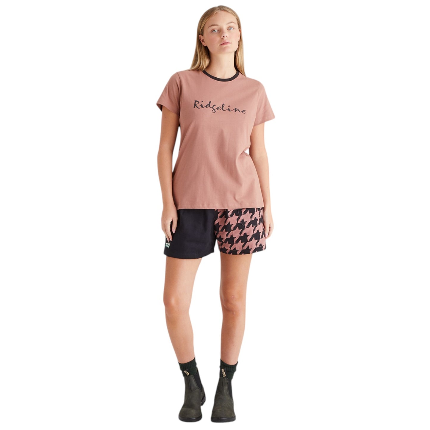 Woman wearing a pink t-shirt and patterned shorts on a white background