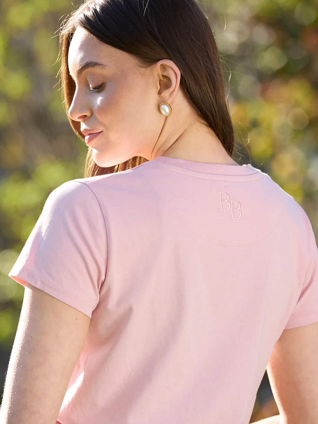 Woman wearing a pink t-shirt with a blurred natural background