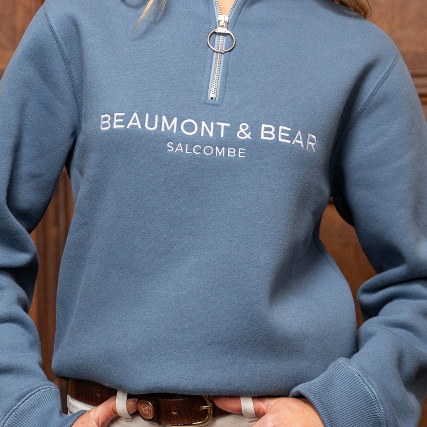 Blue hoodie with 'Beaumont & Bear Salcombe' text on a wooden background