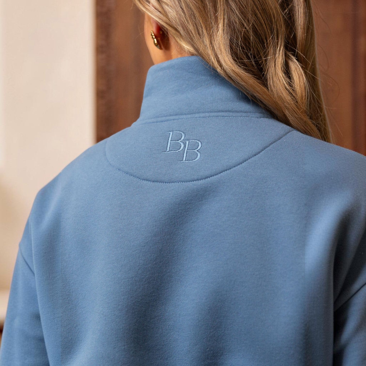 Blue jacket with a logo on the back, worn by a person.