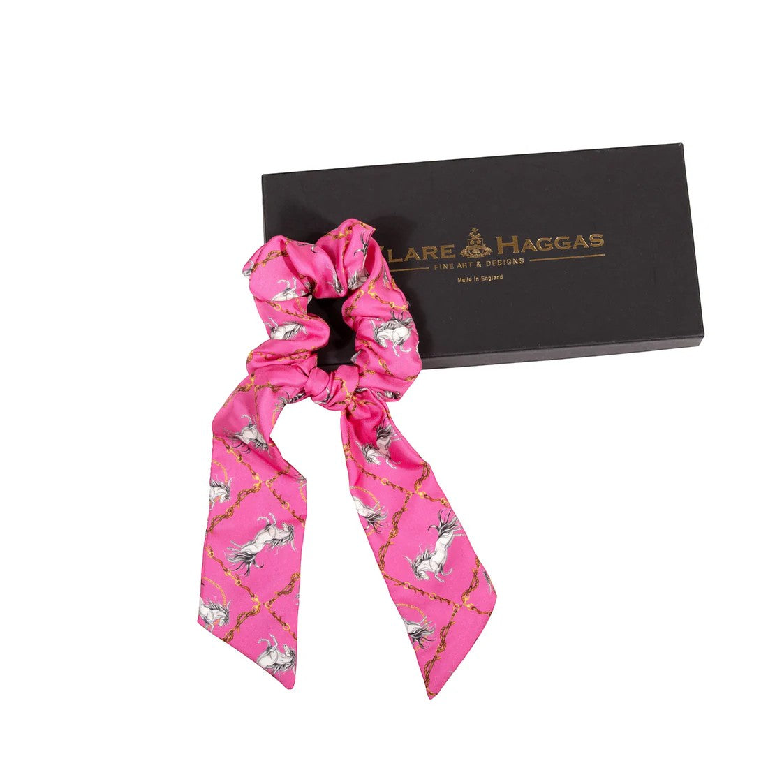 Pink scrunchie with horse pattern in front of a black box with 'Lare & Haggas' branding.