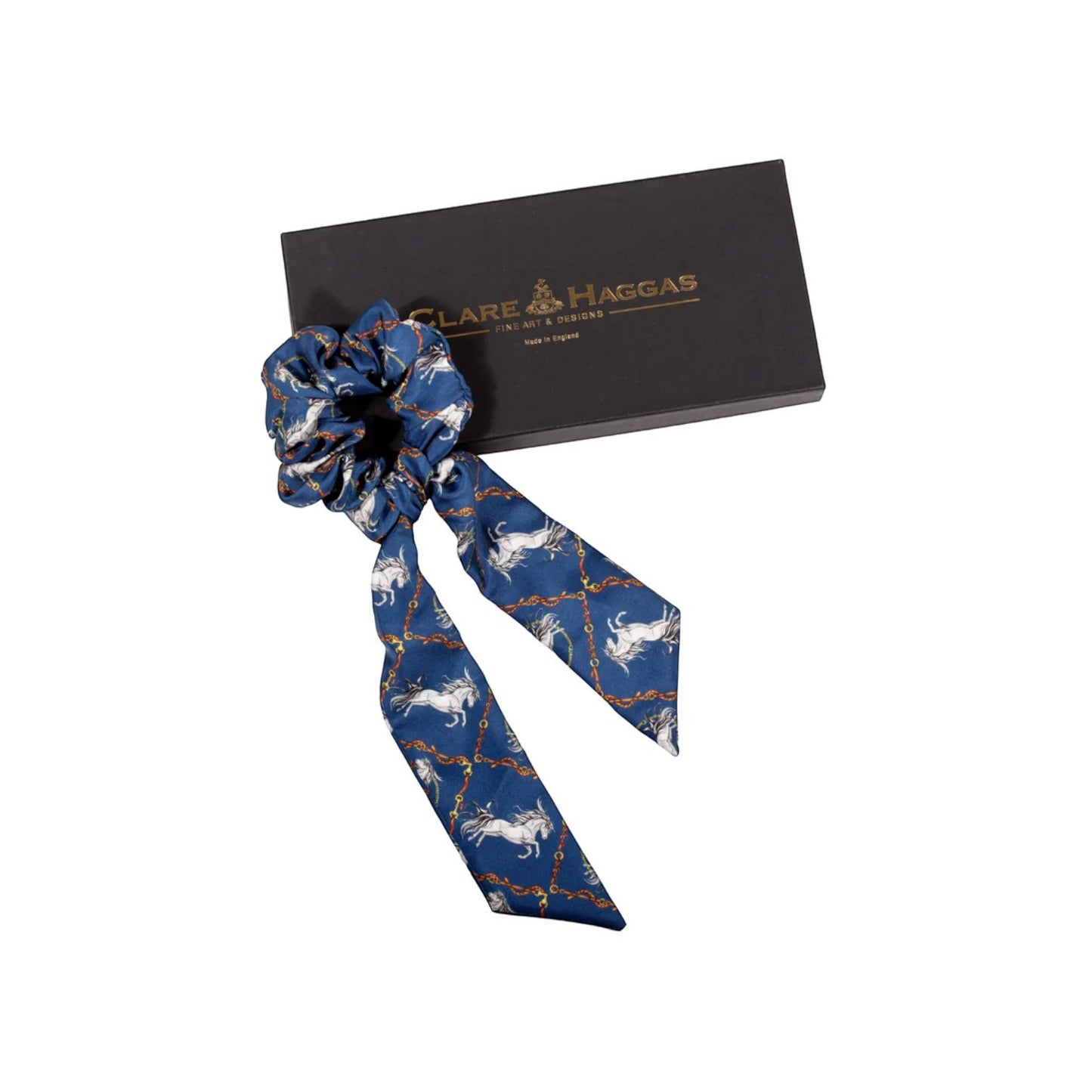 Blue scrunchie with horse pattern in front of Clare Haggas box on white background