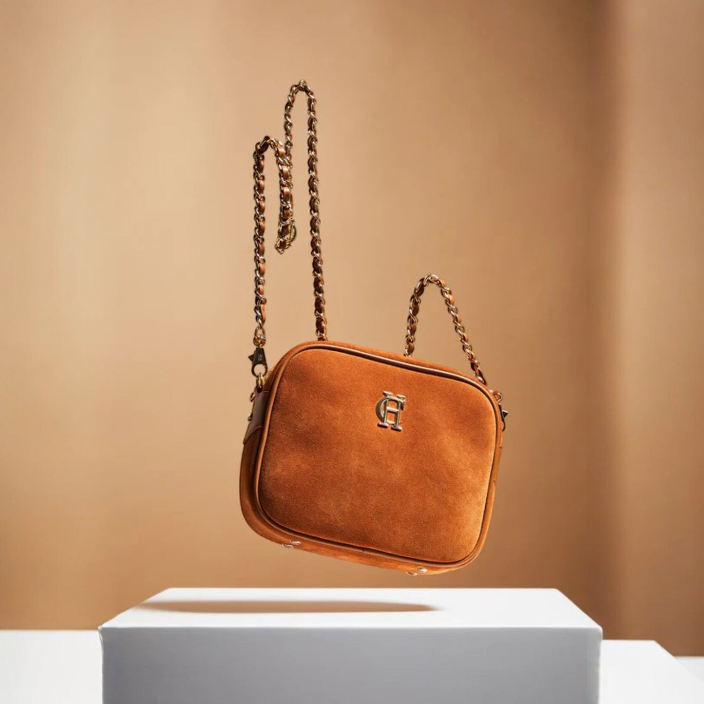 Brown handbag with chain strap on a beige background