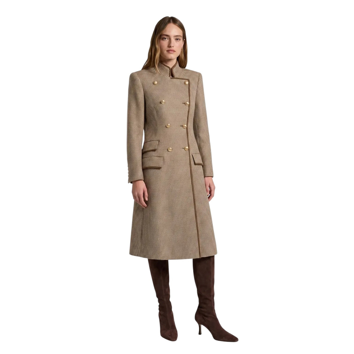A woman modeling a mid-length beige and brown houndstooth double-breasted coat with gold buttons, paired with dark brown knee-high boots, on a solid white background.