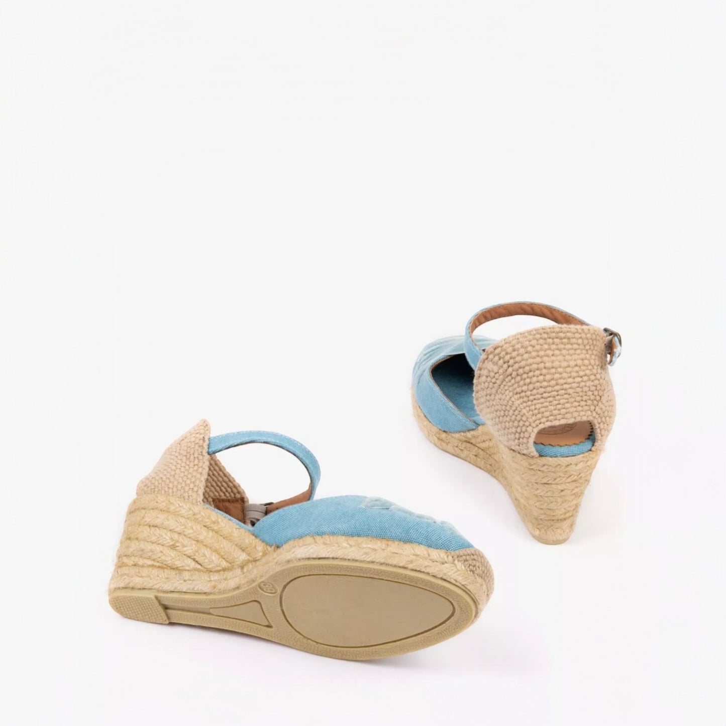 Pair of wedge sandals with raffia wedge and blue suede straps on a white background