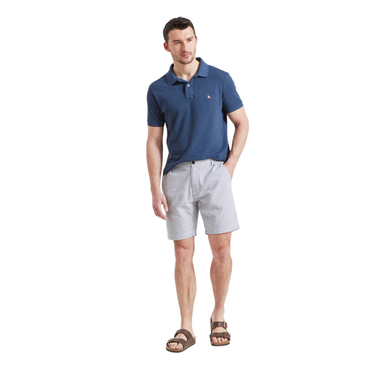 Man wearing a blue polo shirt and light gray shorts on a white background