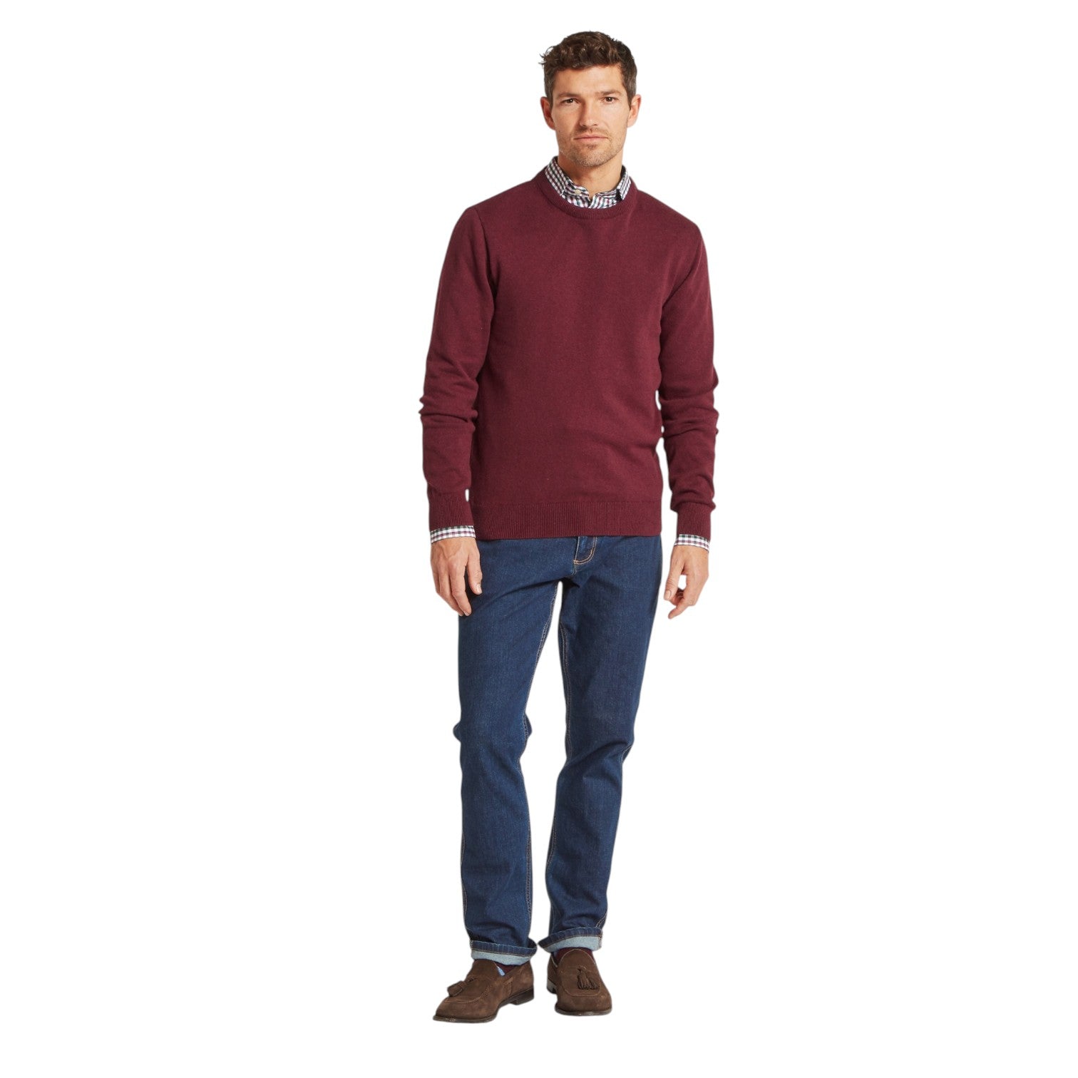 Man wearing a burgundy sweater and blue jeans on a white background