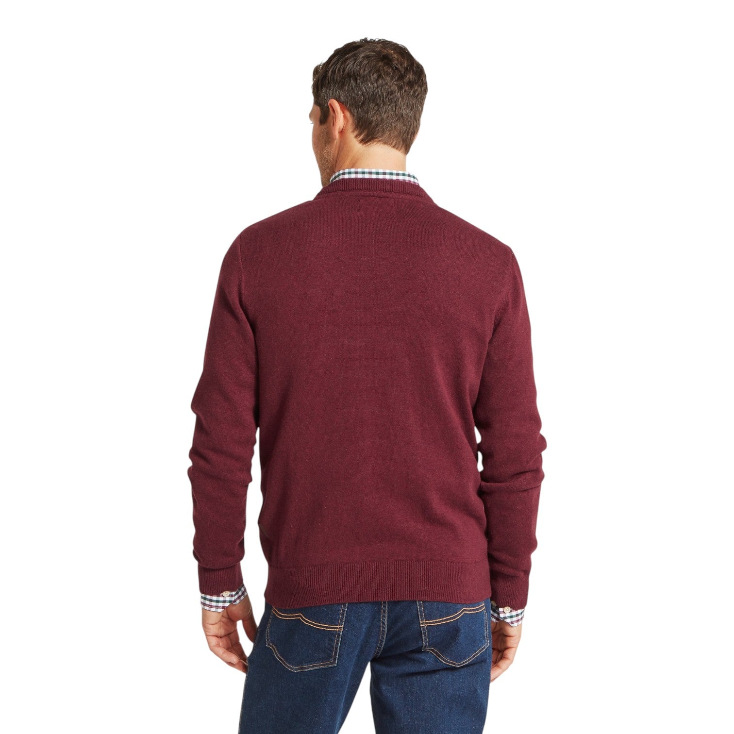 Man wearing a burgundy sweater and blue jeans on a white background