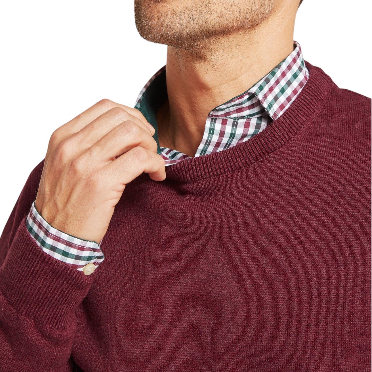 Man wearing a burgundy sweater over a plaid shirt with a white background