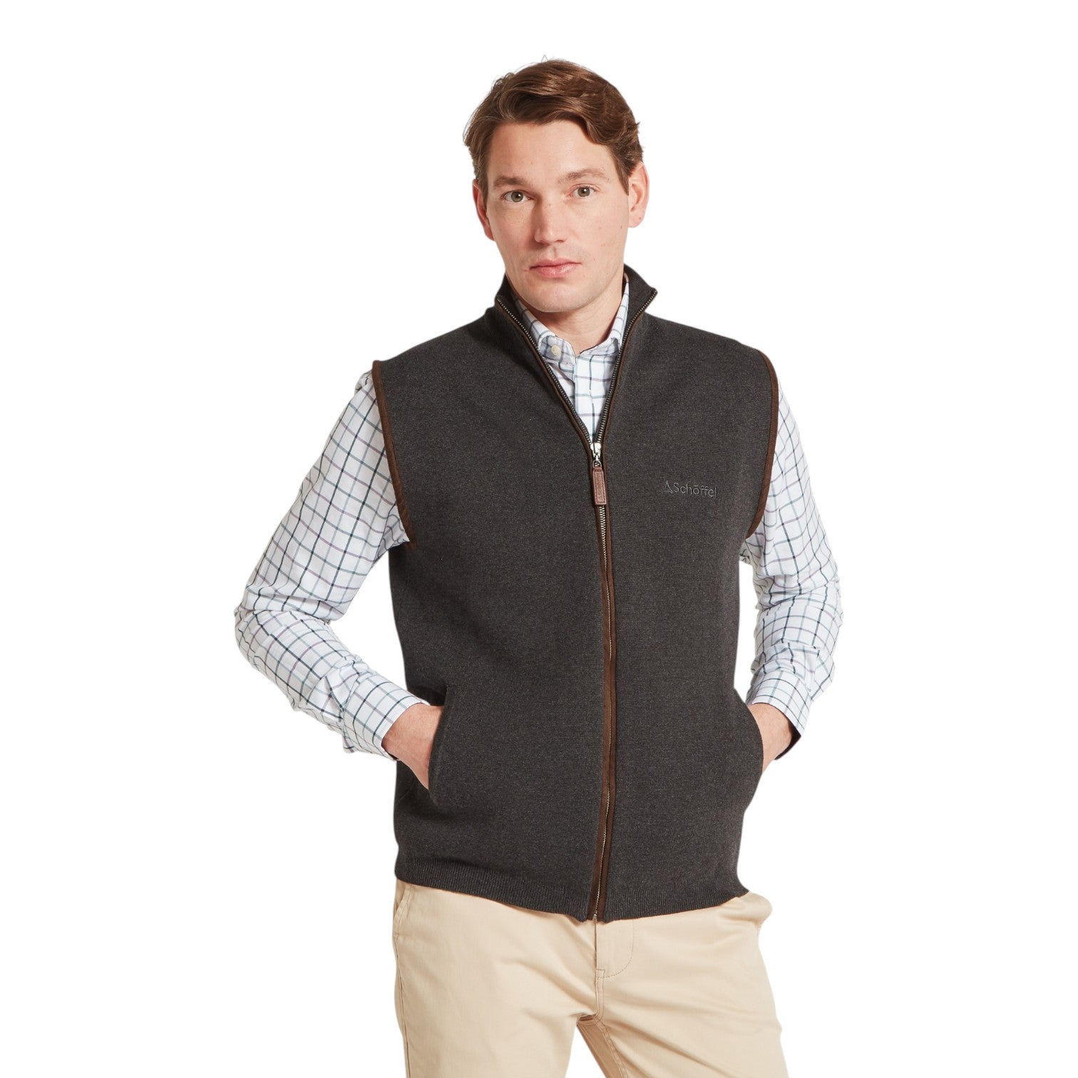 Man wearing a dark gray vest over a checkered shirt on a white background