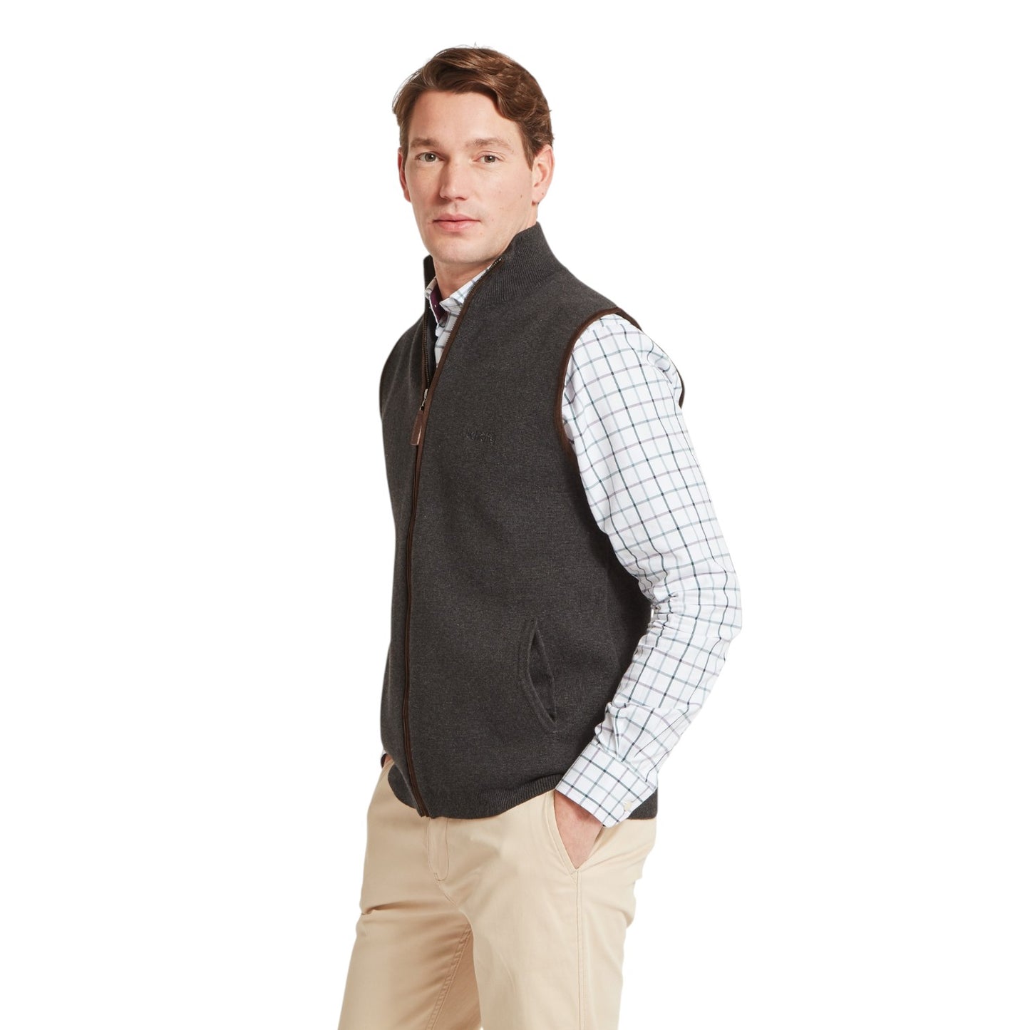 Man wearing a dark gray vest over a plaid shirt on a white background