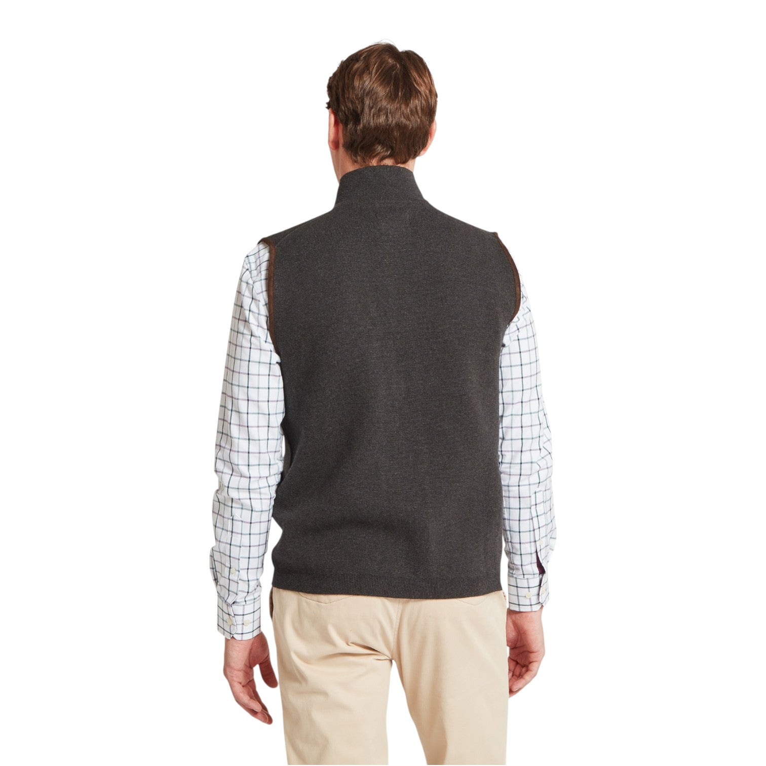 Man wearing a dark gray vest over a plaid shirt on a white background