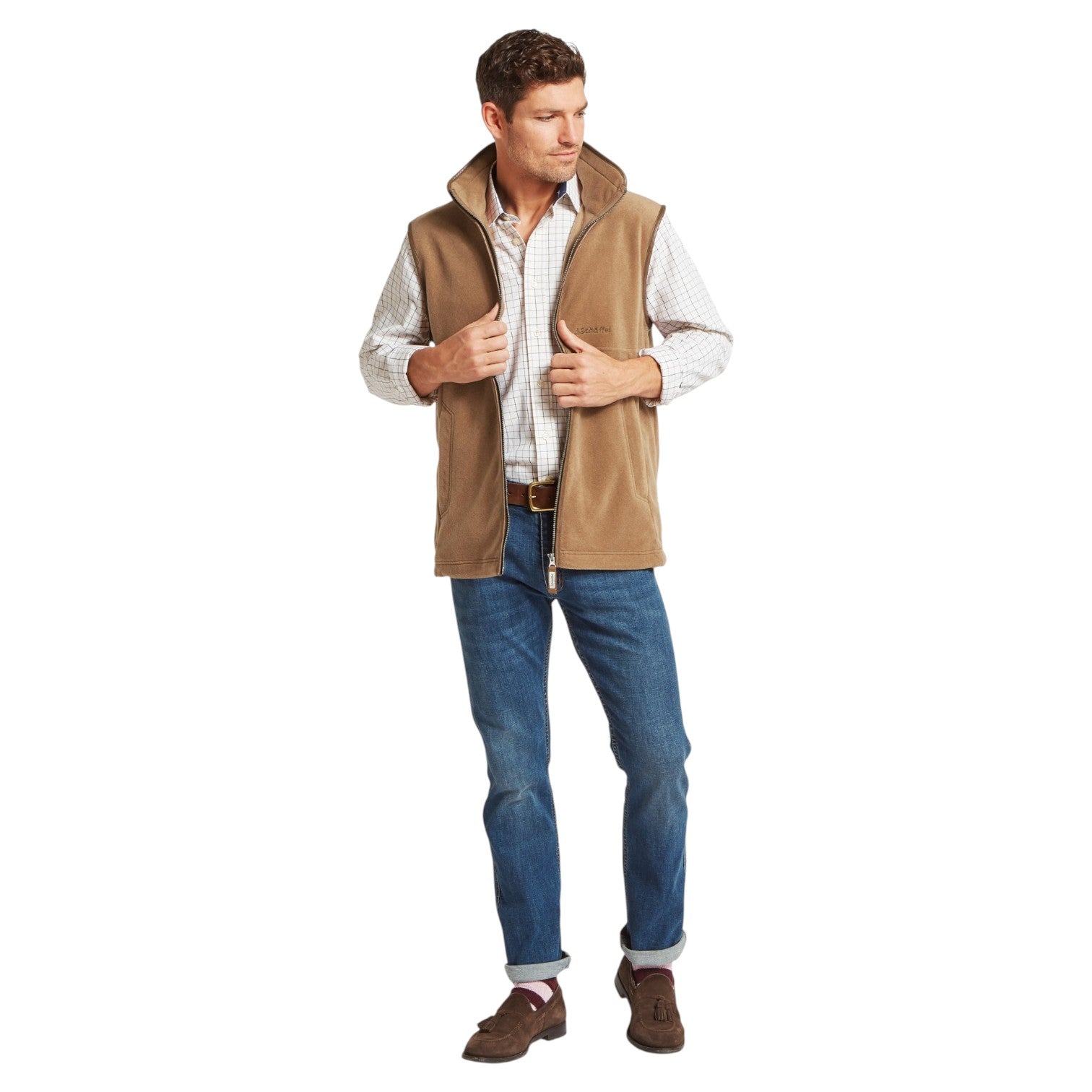 Man wearing a brown vest over a white shirt with blue jeans on a white background