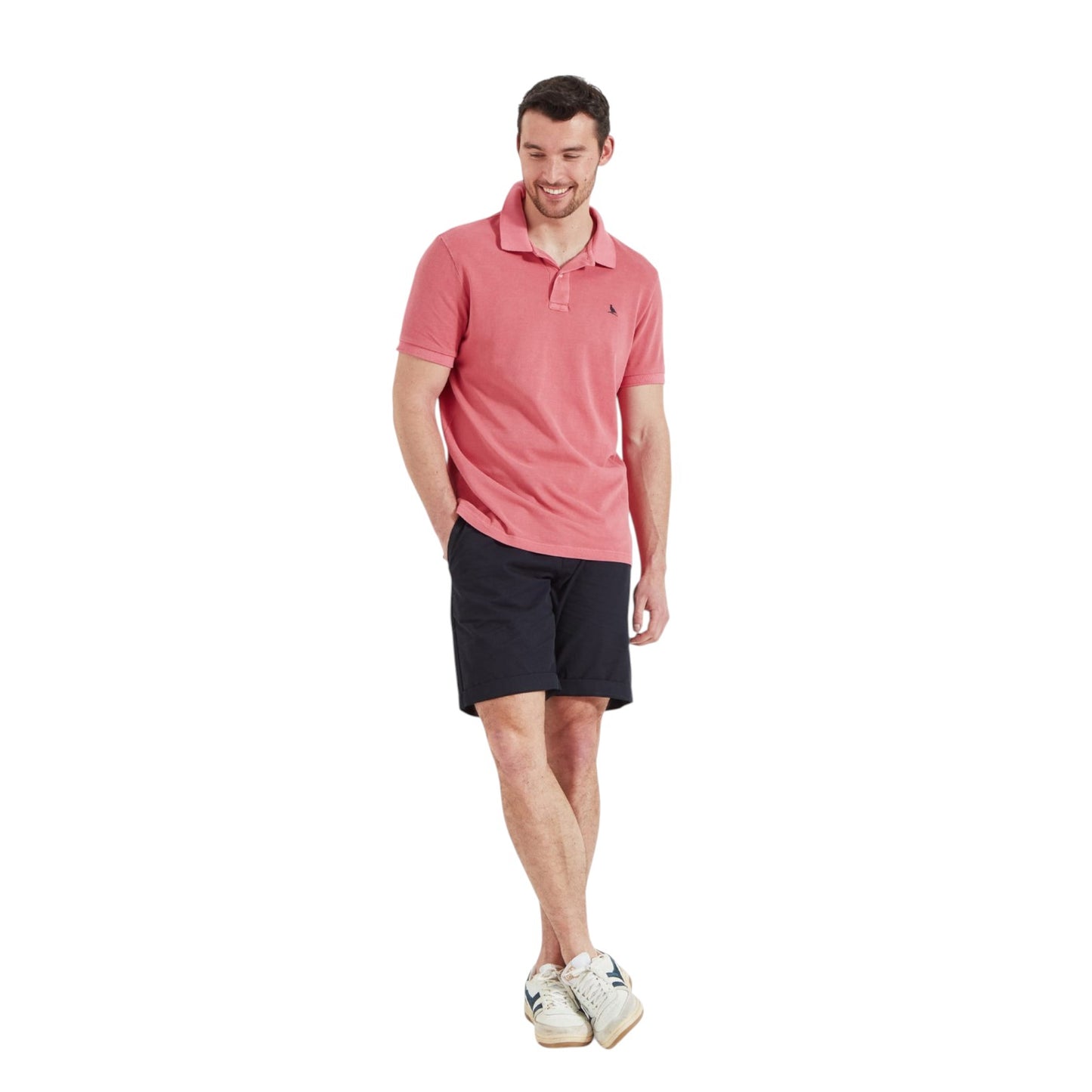 Man wearing a pink polo shirt and black shorts on a white background