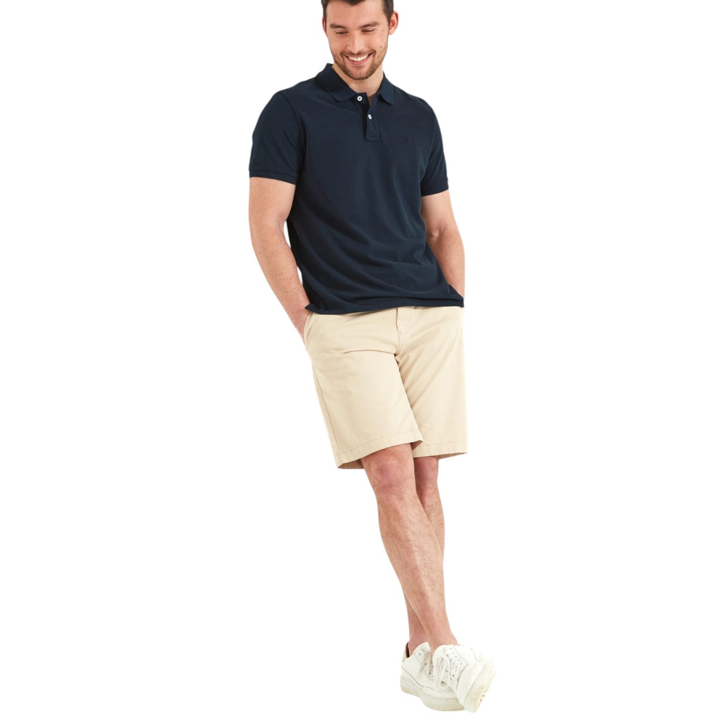 Man wearing a navy polo shirt and beige shorts on a white background