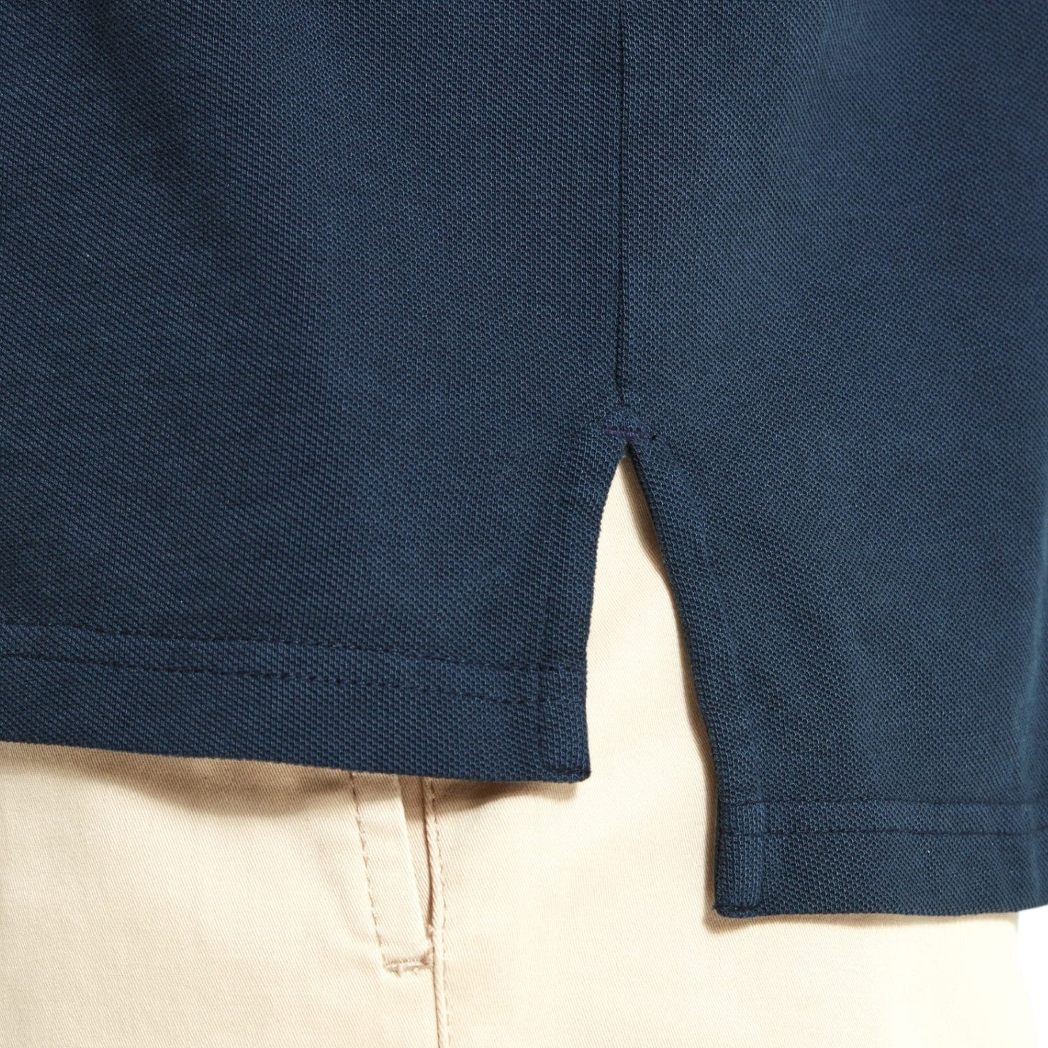 Close-up of navy blue shorts with beige pants underneath on a light background