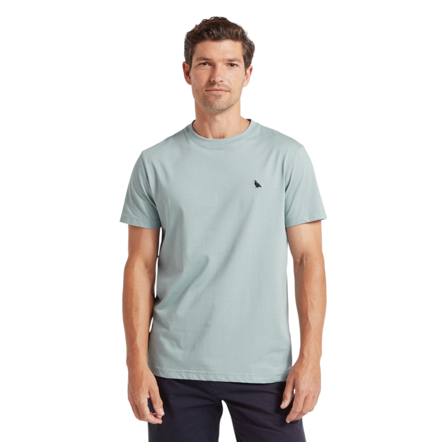 Man wearing a light blue t-shirt with a small black logo on a white background