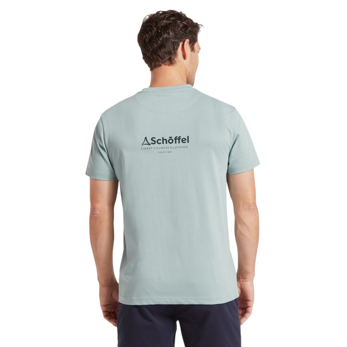 Man wearing a light blue t-shirt with a logo on the back against a white background
