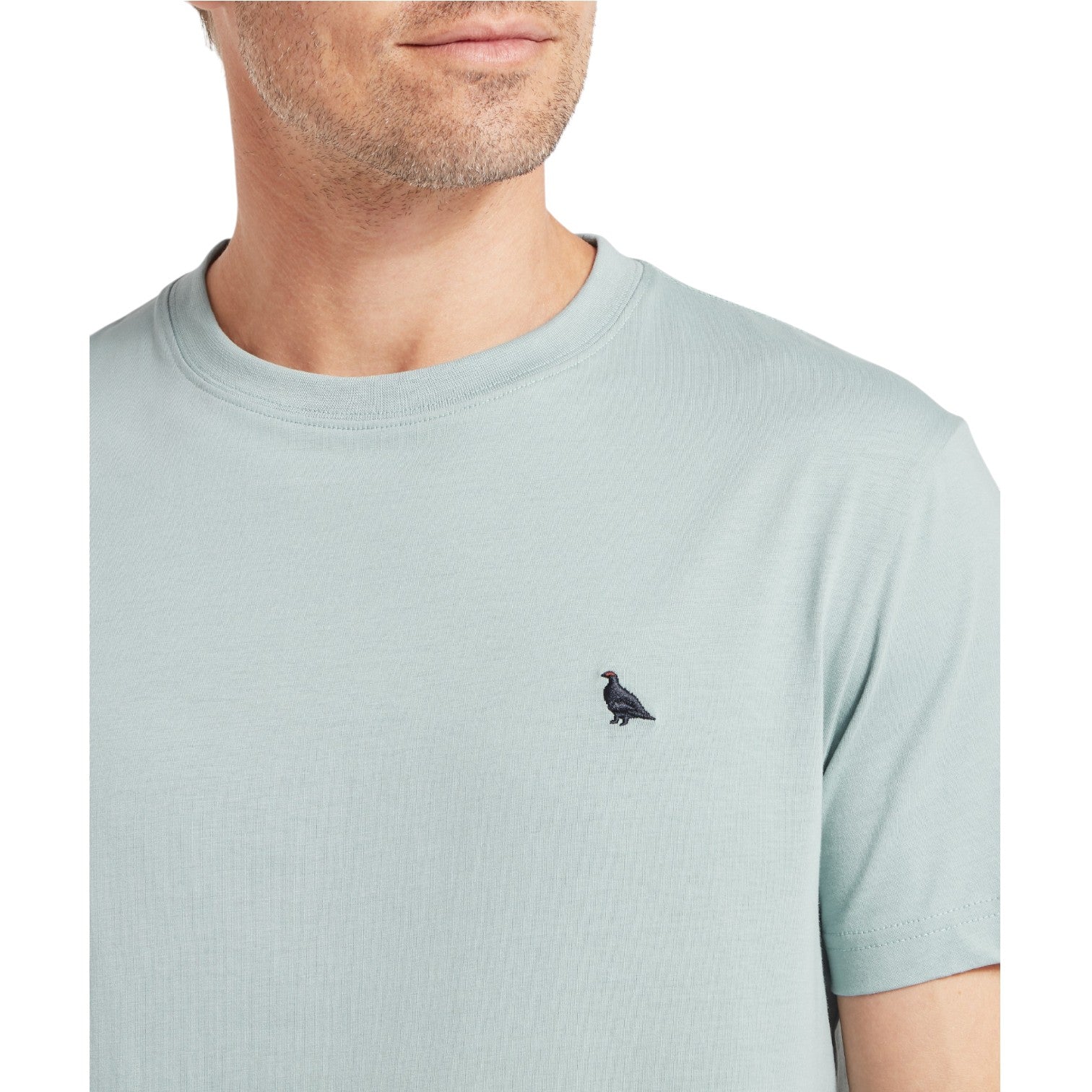 Light blue t-shirt with a small black logo worn by a person on a white background