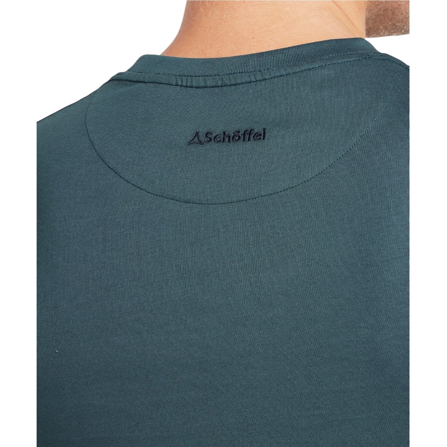 Close-up of a teal shirt with Schöffel logo on the collar against a white background