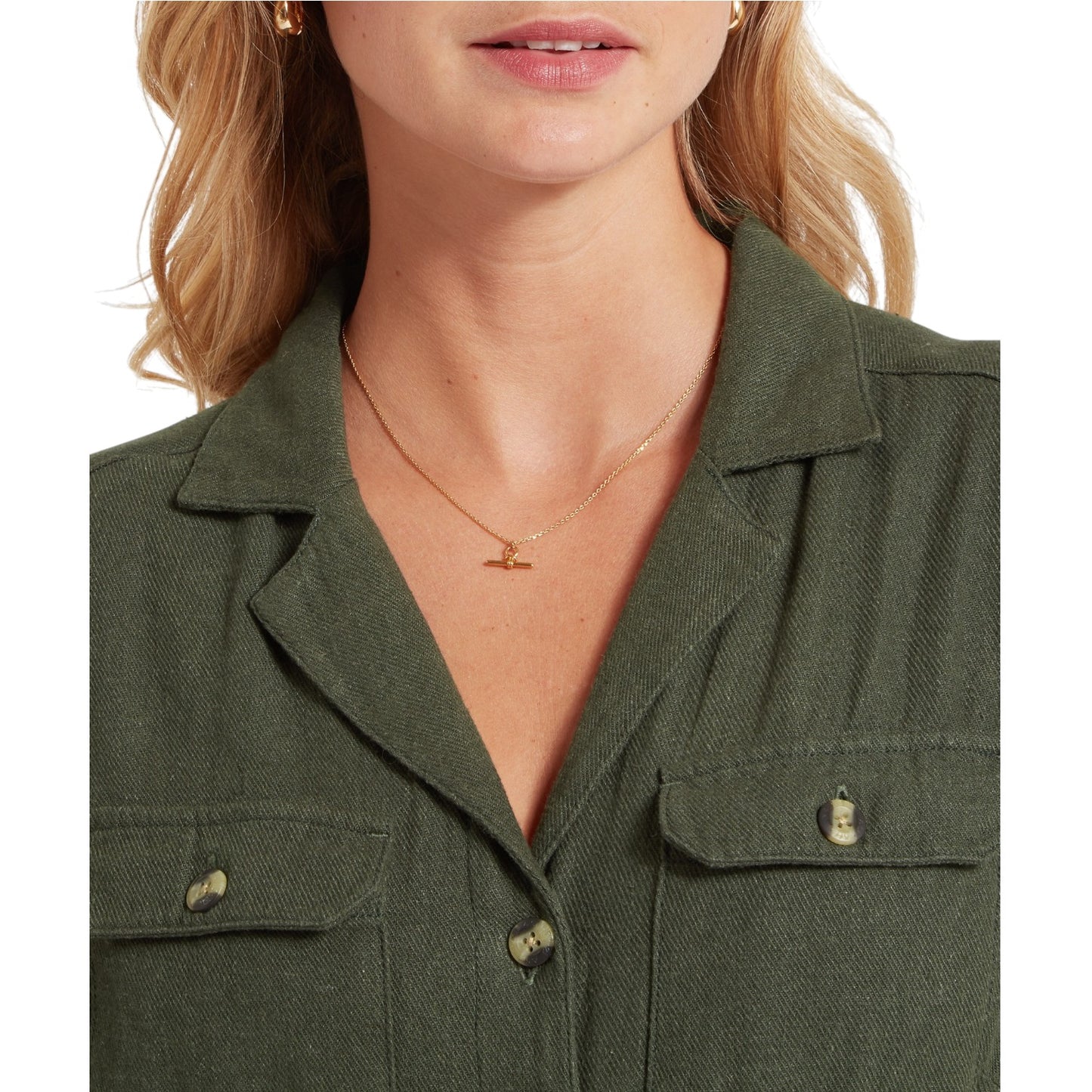 Close-up of a person wearing a green jacket with a necklace featuring a small pendant.