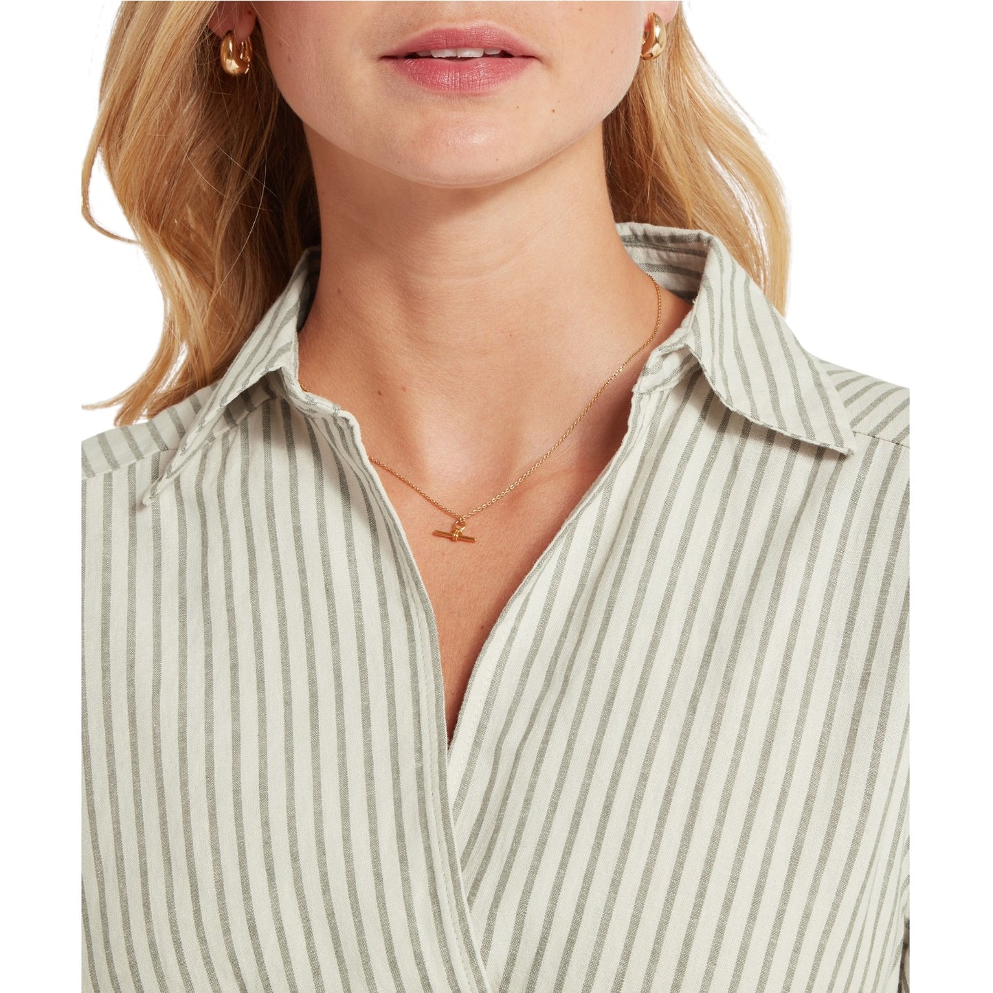 Close-up of a person wearing a striped shirt with a necklace and earrings.