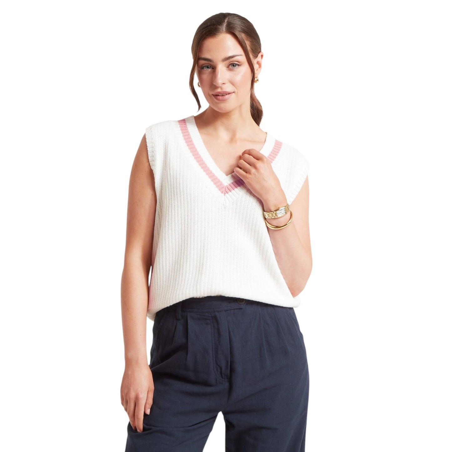 Woman wearing a white sleeveless top with pink trim and navy pants on a white background