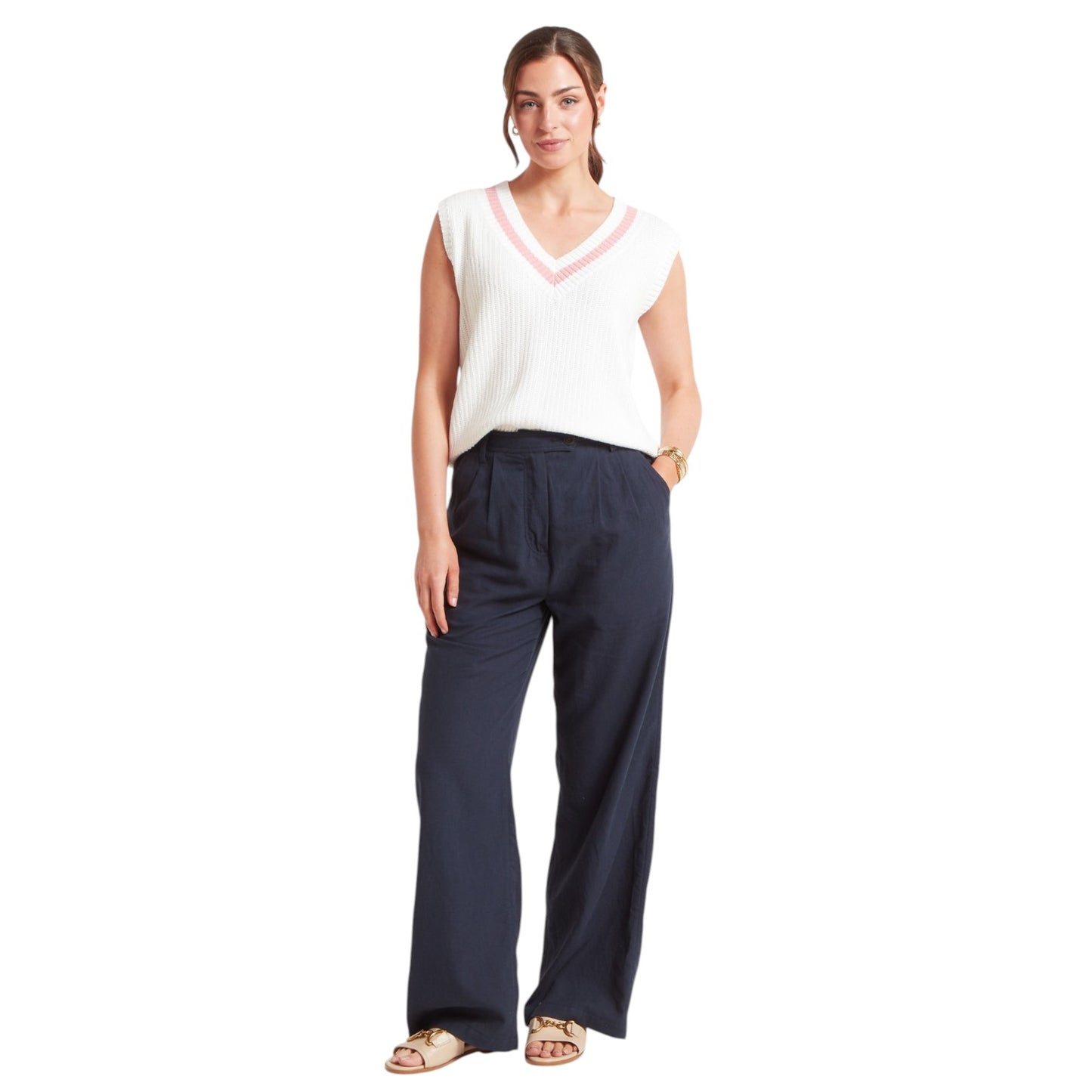Woman wearing a white sleeveless top and navy pants on a white background